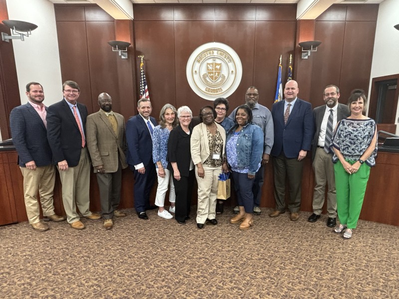 Group of people posing for a photo in a board room.