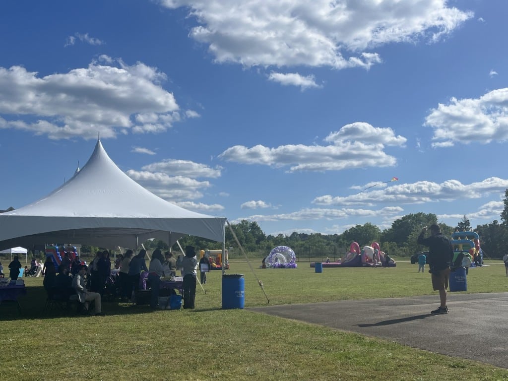 an outdoor scene in a park, with a tent, and inflatable bounce houses