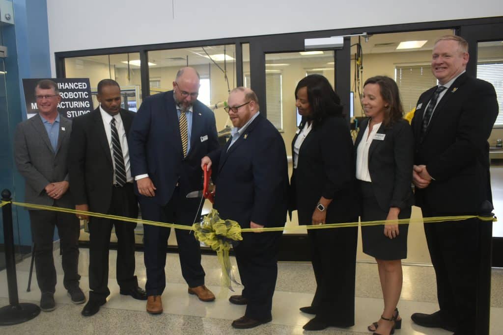 A group of people in front of a robotics lab cutting a ribbon