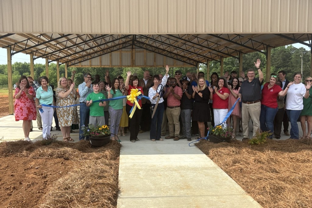 A group of people gather around a ribbon and celebrate the ribbon cutting.