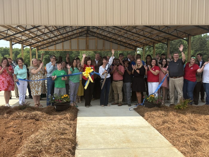 A group of people gather around a ribbon and celebrate the ribbon cutting.
