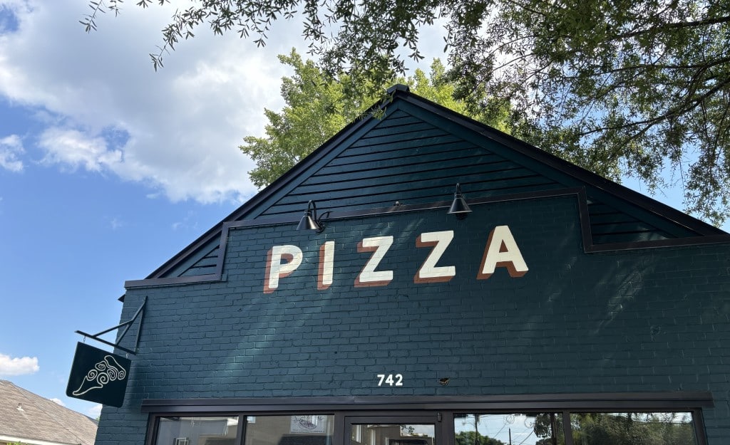 green brick and mortar building with pizza in capital letters across it