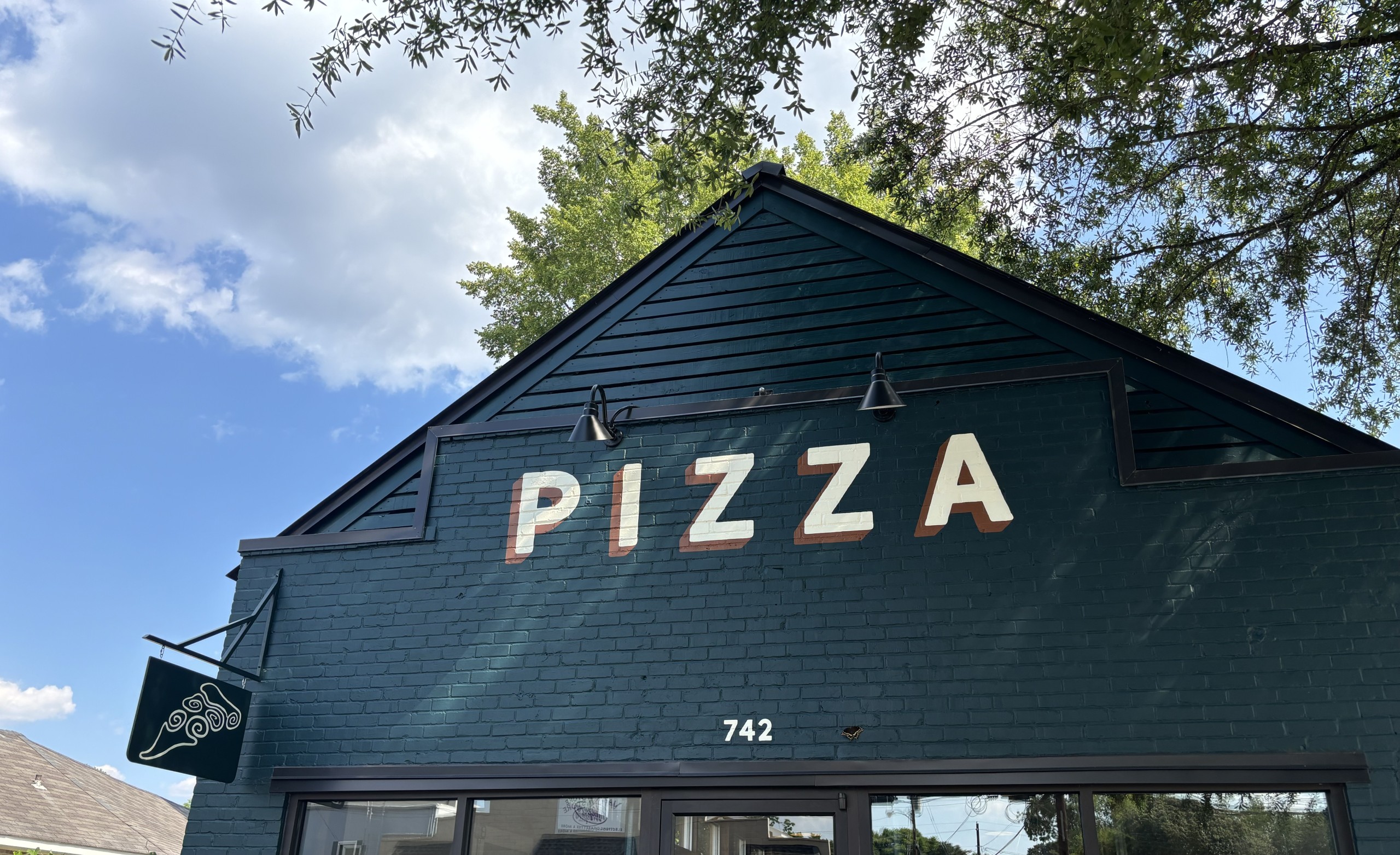 green brick and mortar building with pizza in capital letters across it