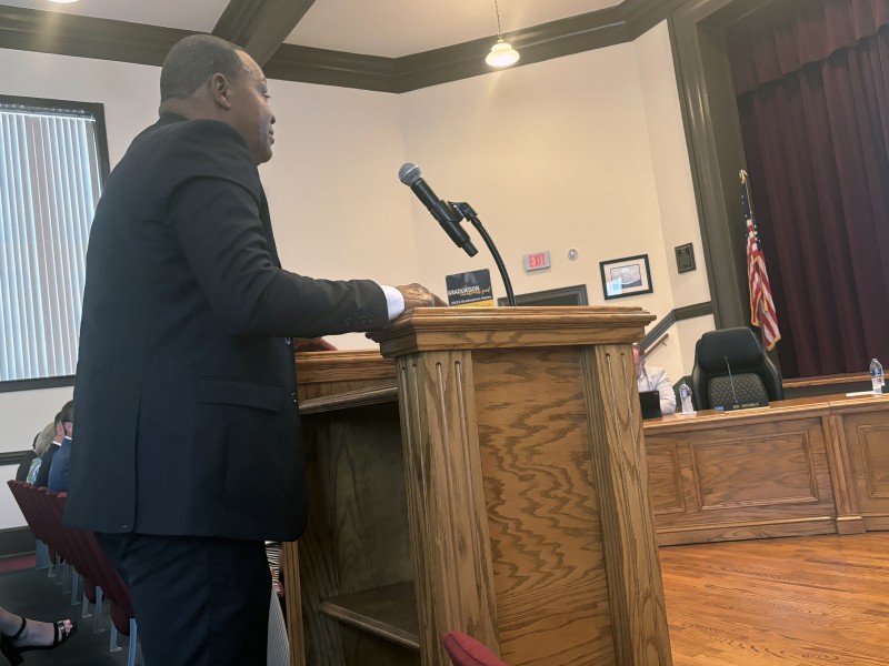 African American male wearing a suit speaking into a microphone