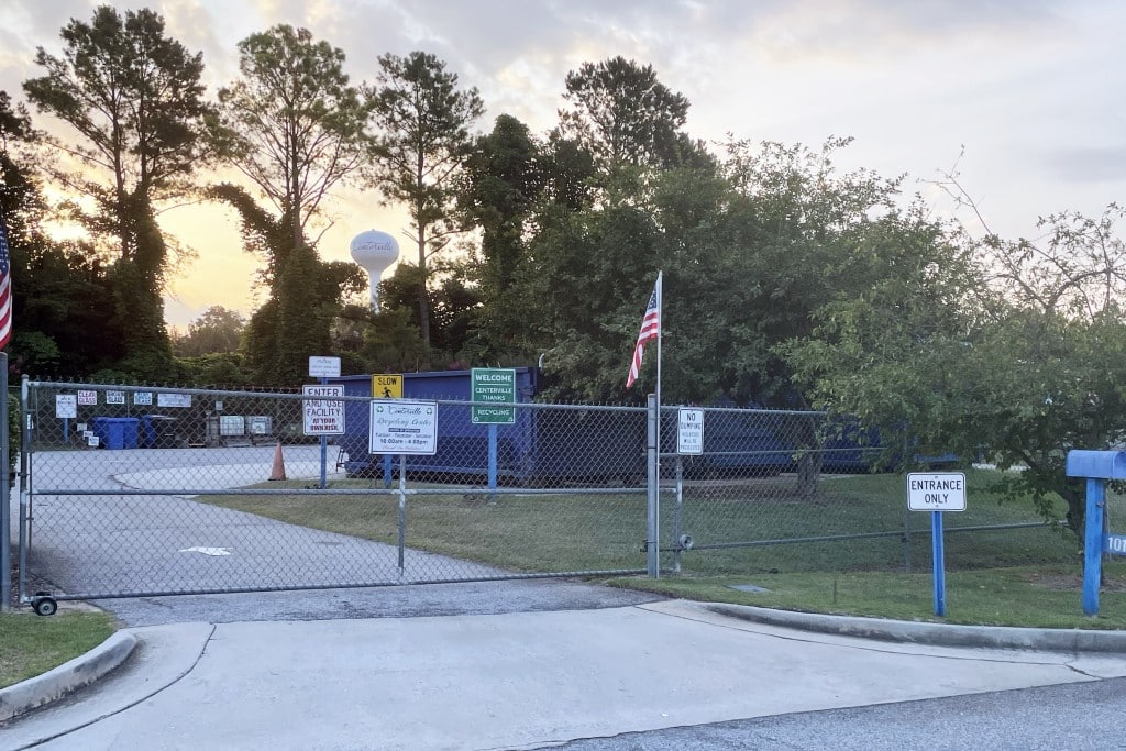 Photo of outside the recycling center. There is a fence and the water tower in the background.
