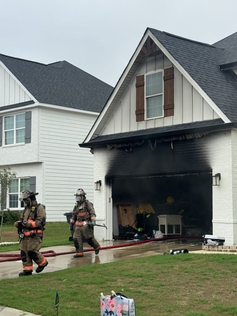 two firemen walking away after extinguishing a fire from the garage, heavily damaged home