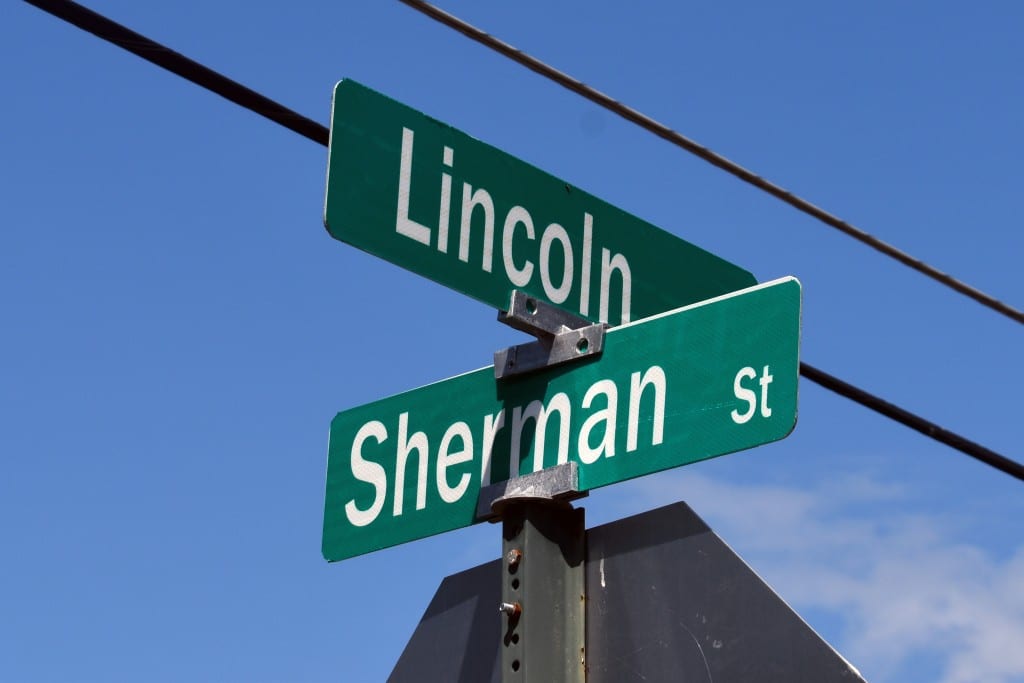 Photo of a street sign with the names Lincoln and Sherman written in white letters.