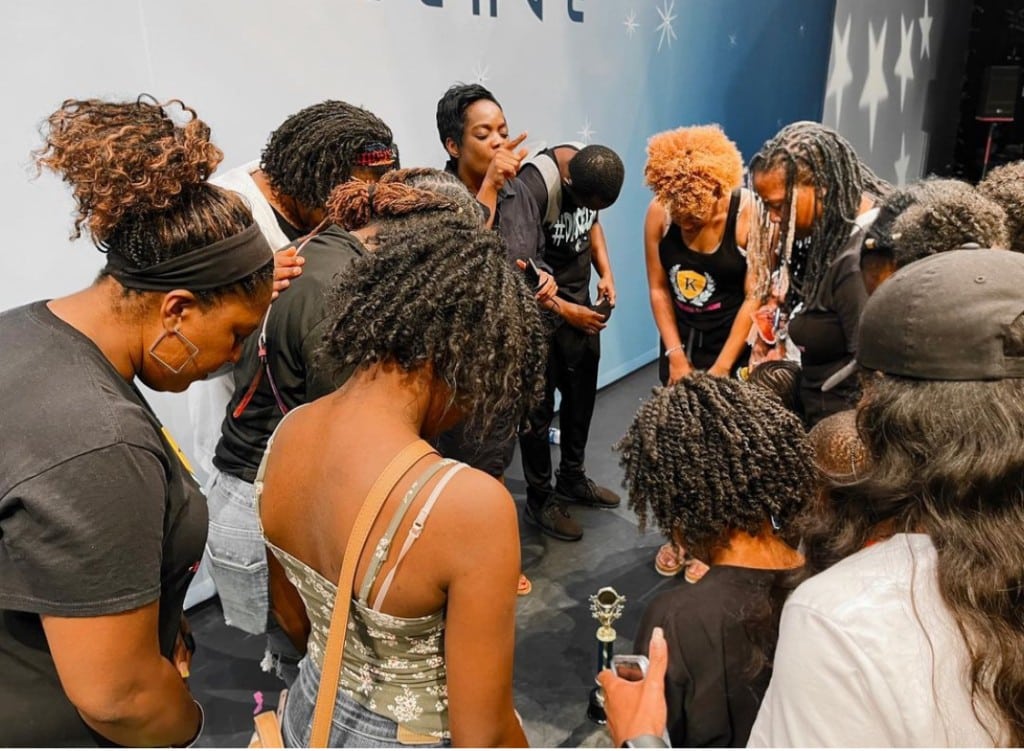 A group of women huddled and praying together on stage.