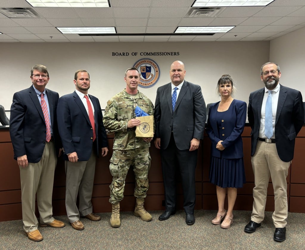 group of six people five men and one woman, four of the men wearing suits and one in a military uniform