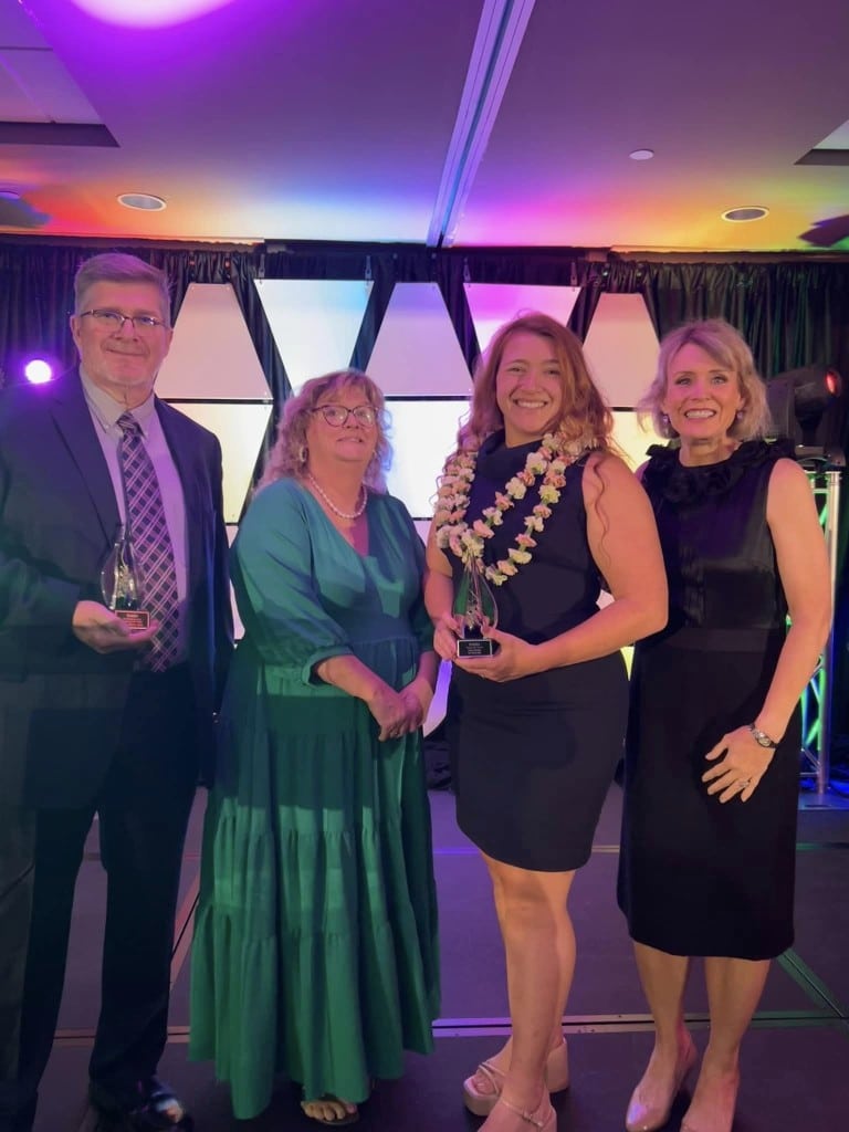 A group of people, three women and a man, smile for the camera.