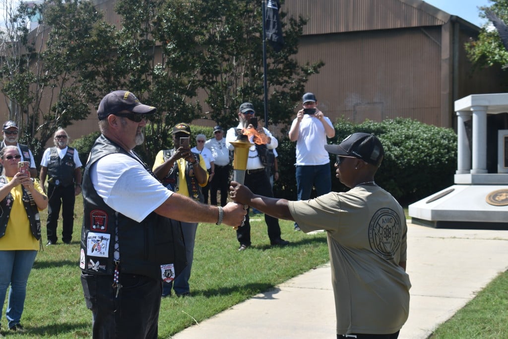 A shorter women and taller man passing a torch.