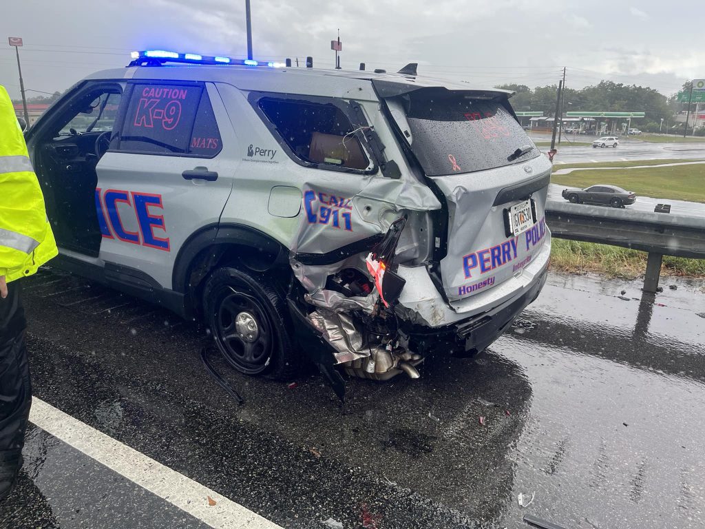 a police vehicle on the side of the roadway with extensive damage to the left rear bumper.