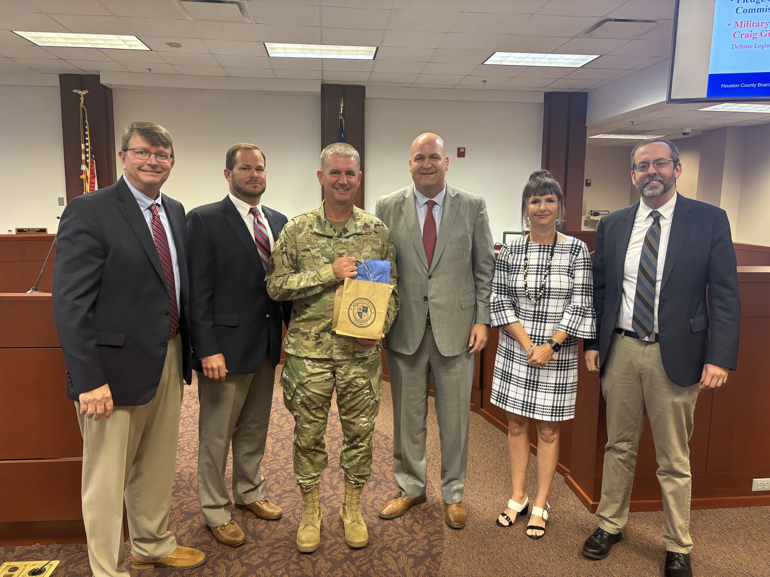 men and women, men wearing suits and one man dressed in a military uniform