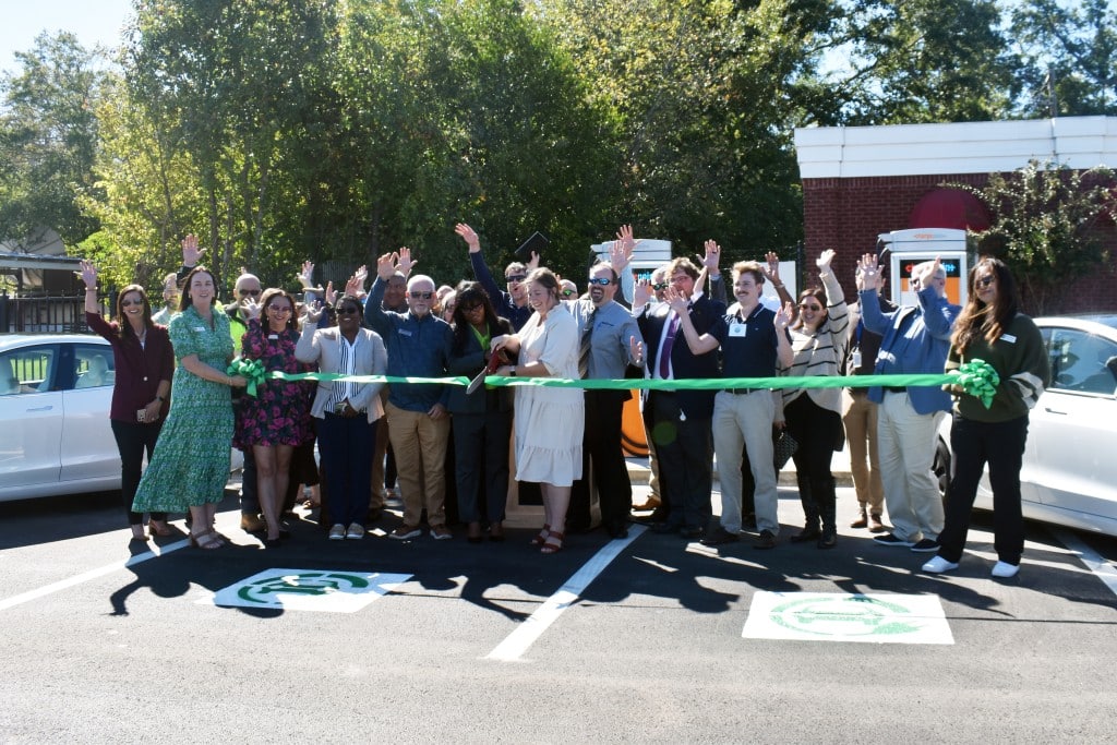 A group of people cutting a green ribbon.