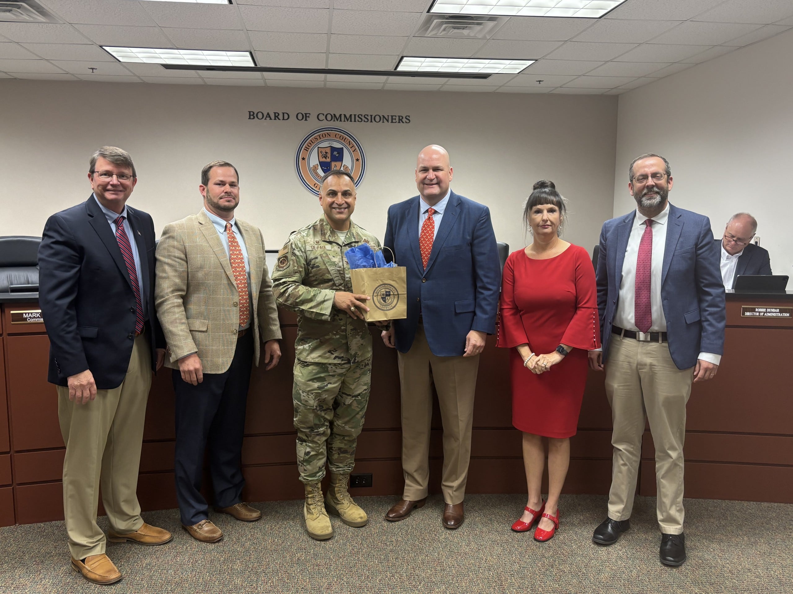men wearing suits and one woman wearing a red dress with a male wearing a military uniform