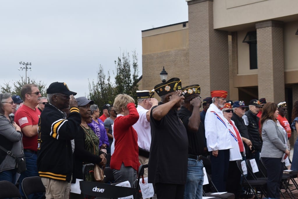 Men and woman standing and saluting.