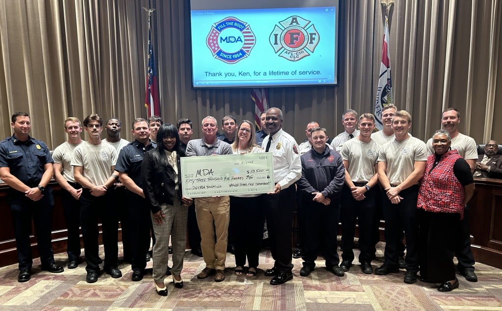A group of people posing for a photo. Three people in the middle are holding a big check.