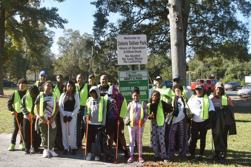 A group made up of both adults and children standing in front of the park's sign.