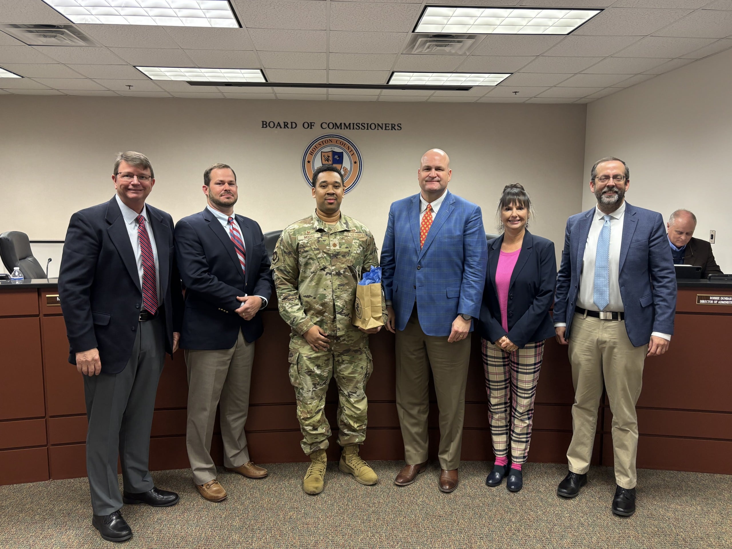 four men wearing suits, one man wearing a military uniform and one woman in a group photo