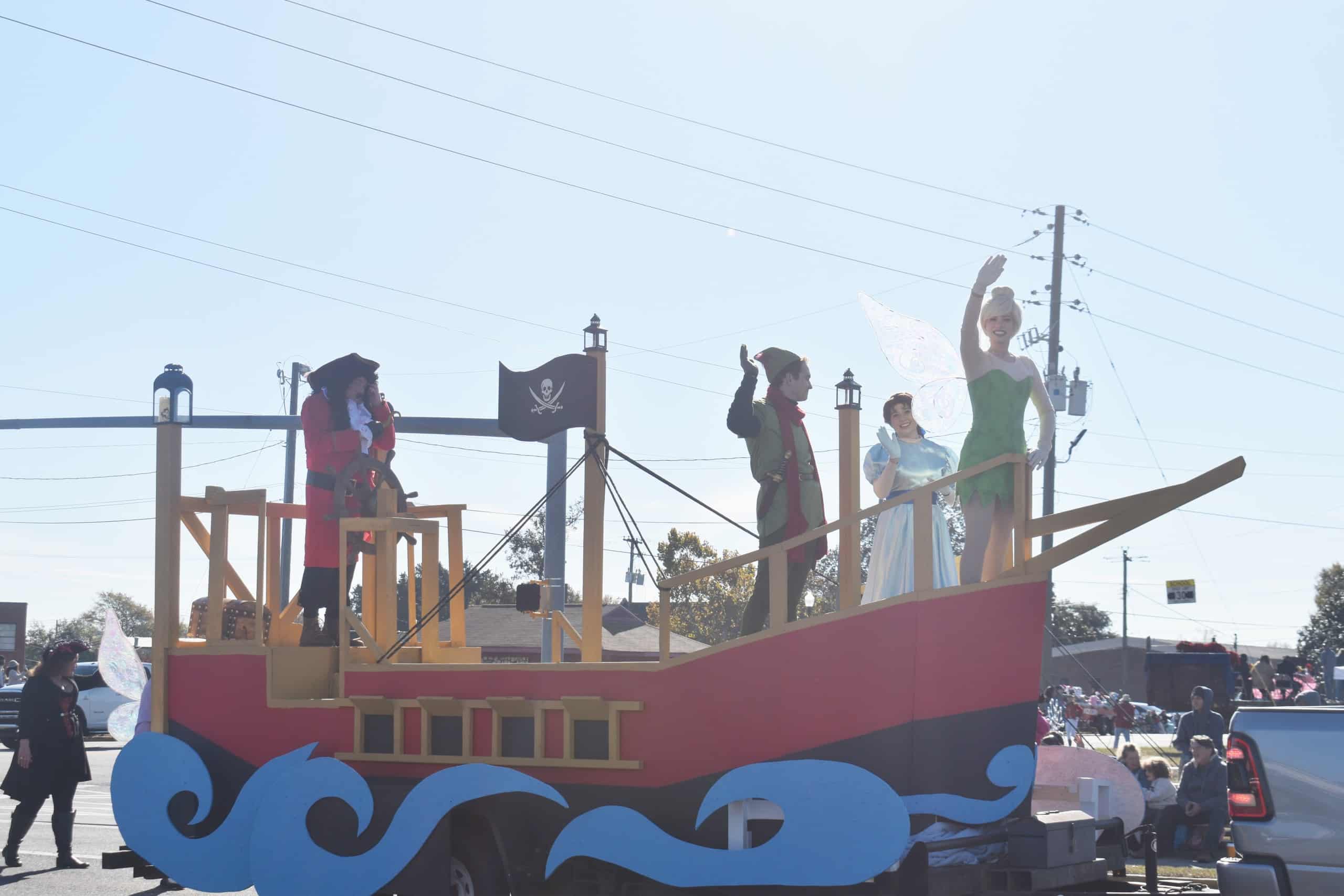 A float decorated as a pirate ship from Peter Pan. Characters like Tinker Bell and Captain Hook are on the float.