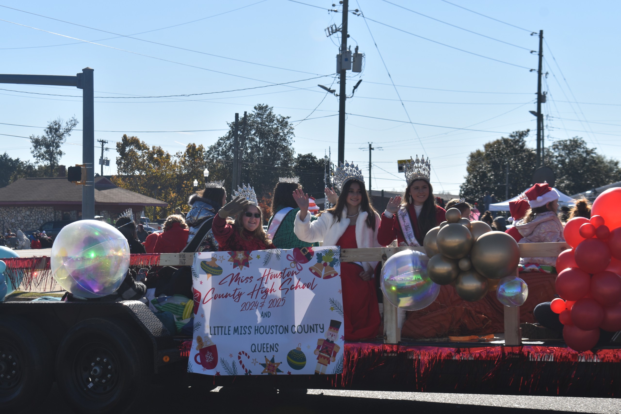 Little Miss Houston County Queens sitting on a float waving at the crowd.