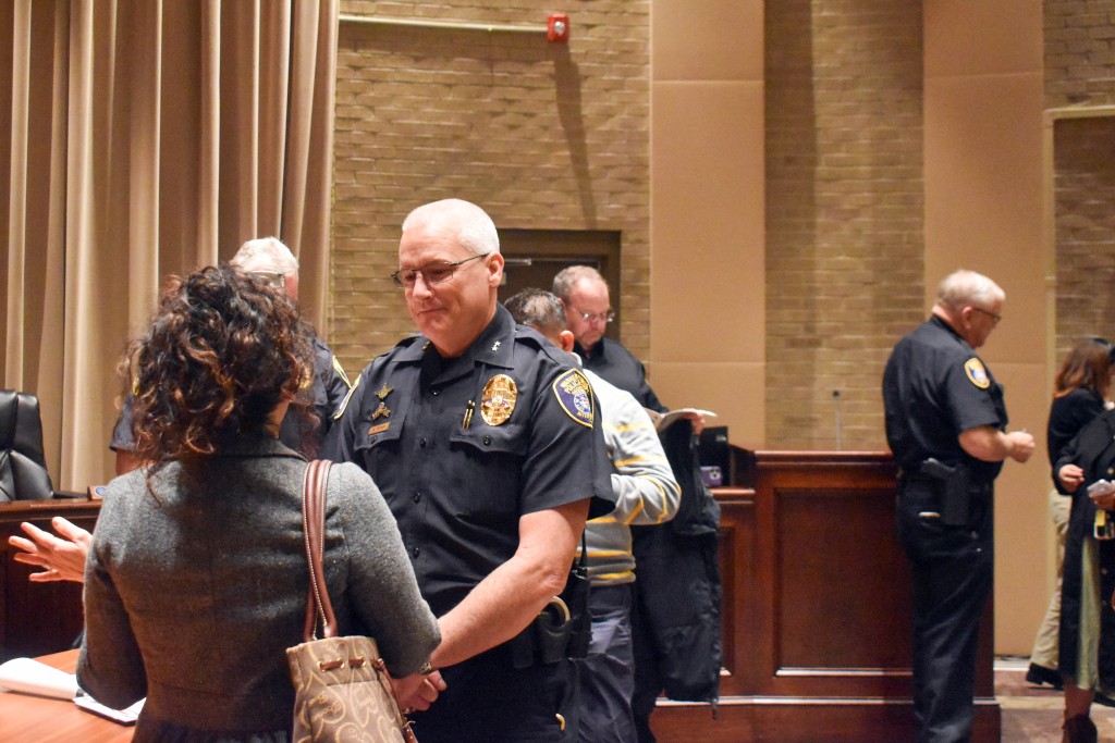 A man in a police uniform is speaking to a woman after a meeting.