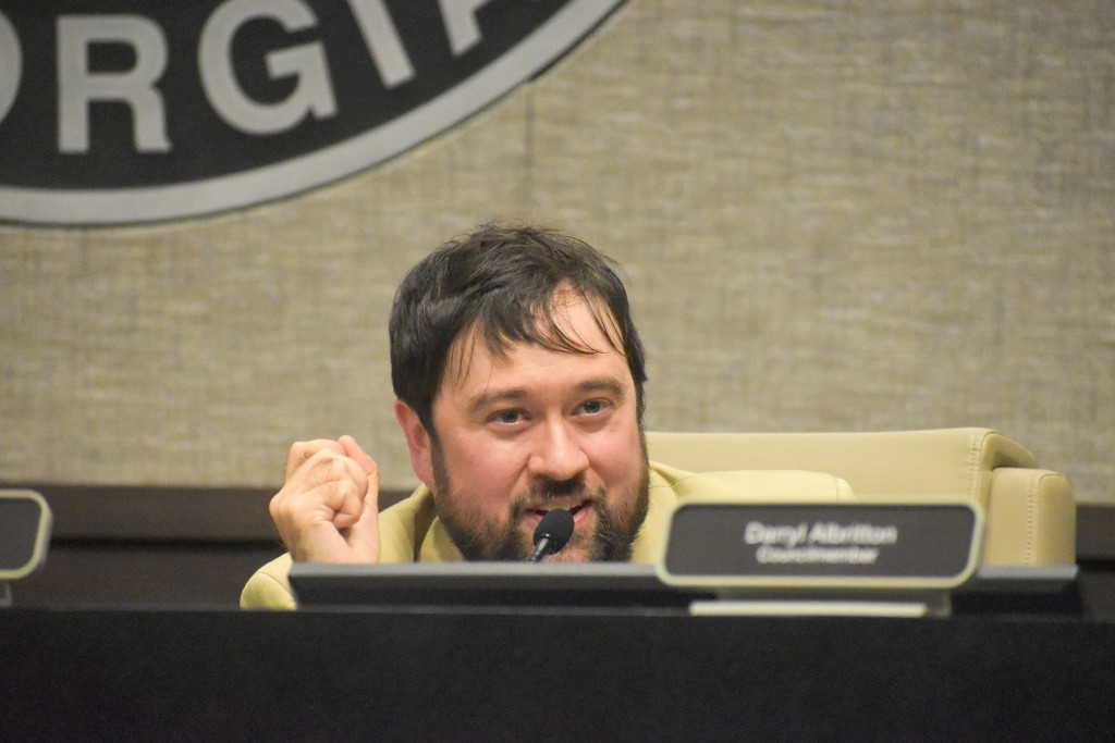 A man sitting behind a table speaking to the audience.