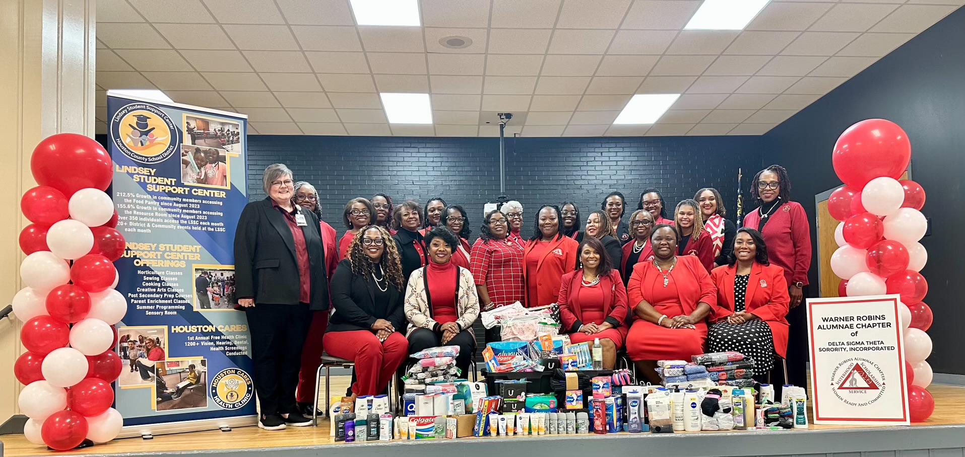 A group of women standing on a stage. In front of them are various hygiene products.