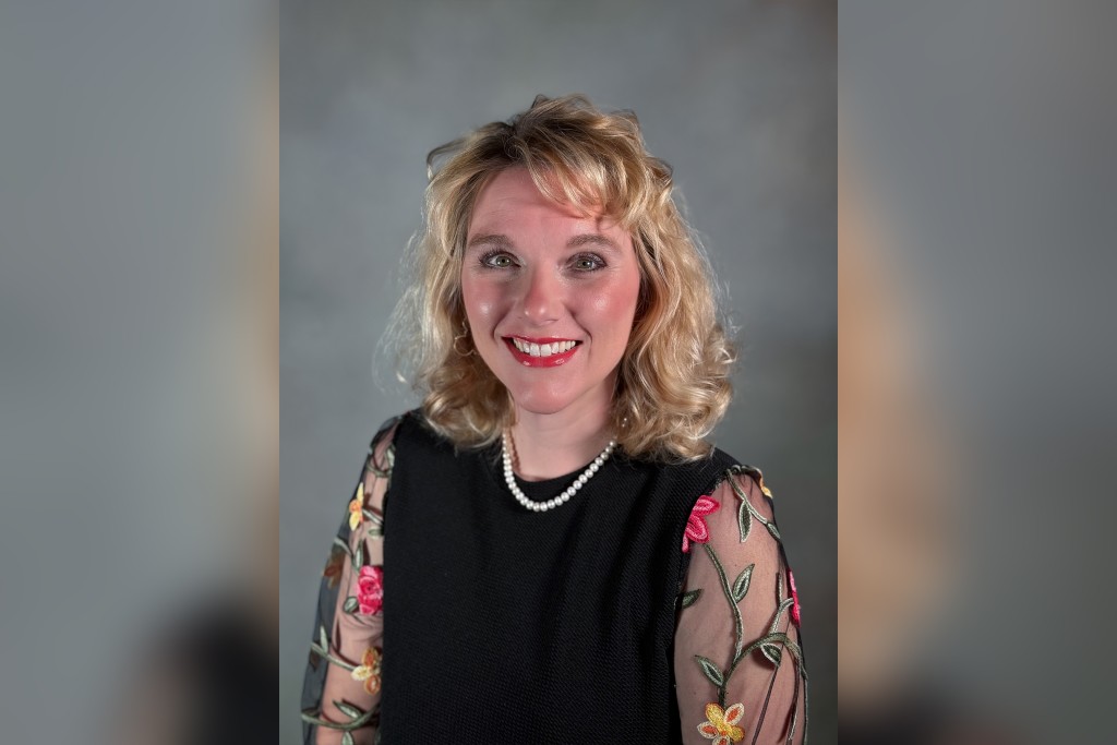 A blonde women in a black dress smiling at the camera.