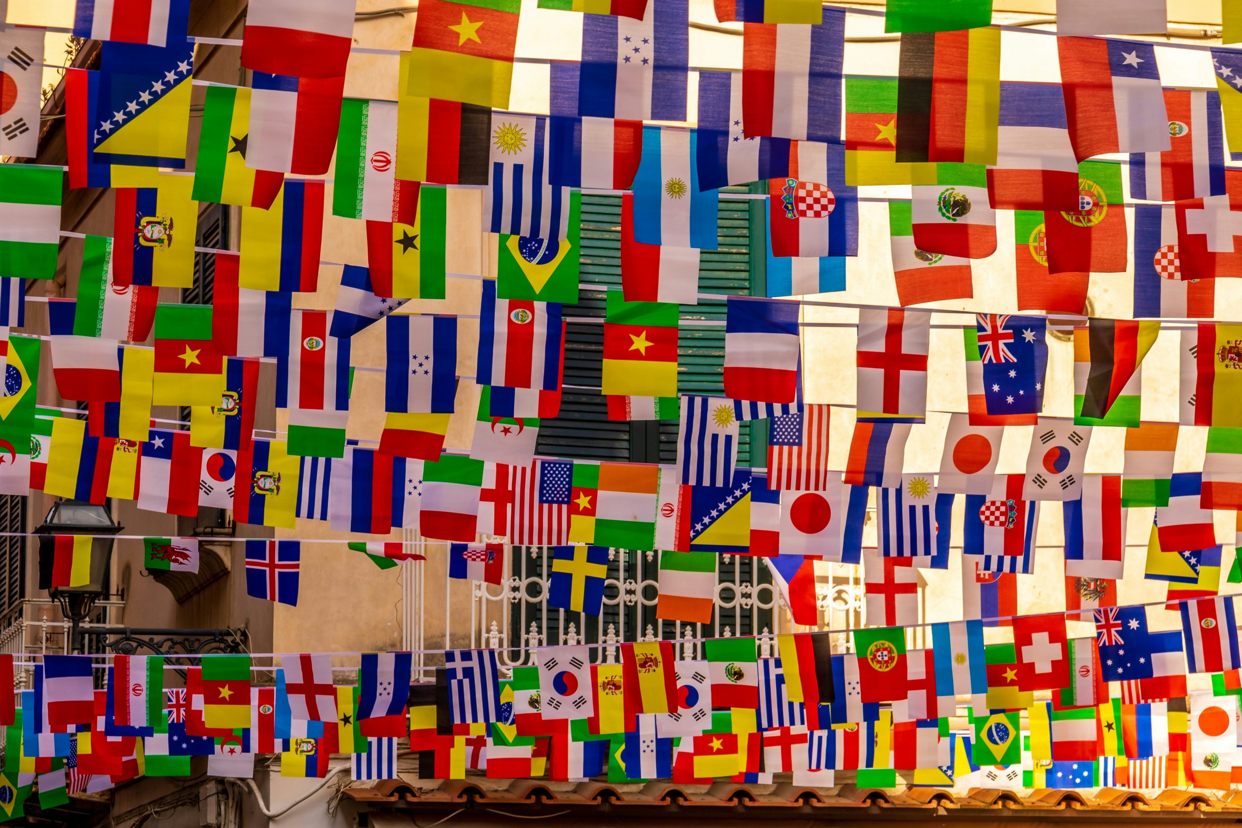 Flags of different countries being displayed in an alley.