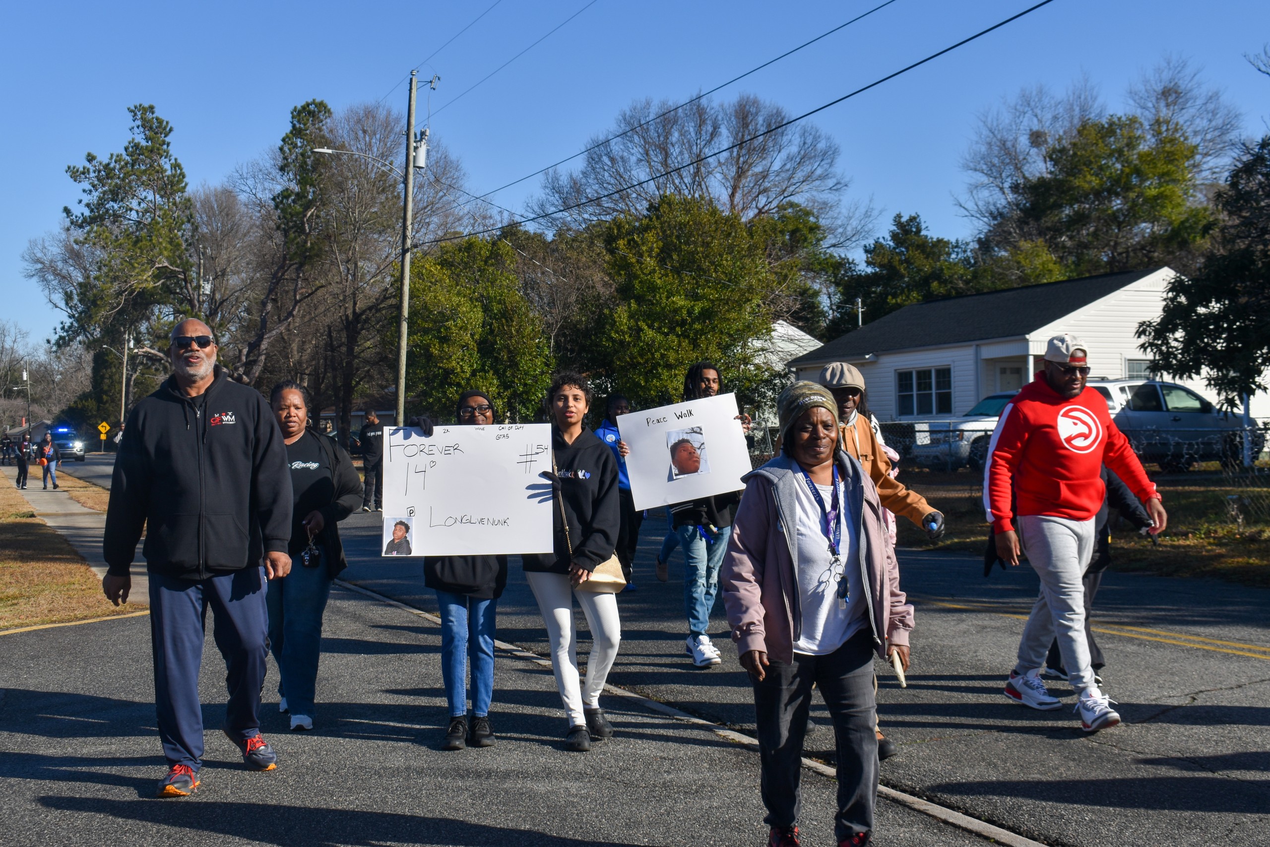 A group of people walking. Two of them are holding a sign.