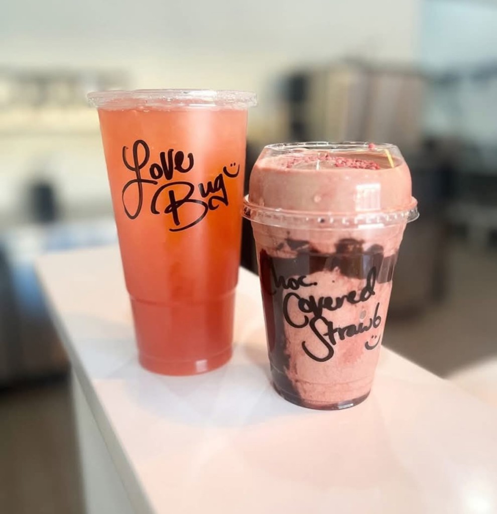 A red drink with the words "Love Bug" written on it. A smaller pink shake is beside it.