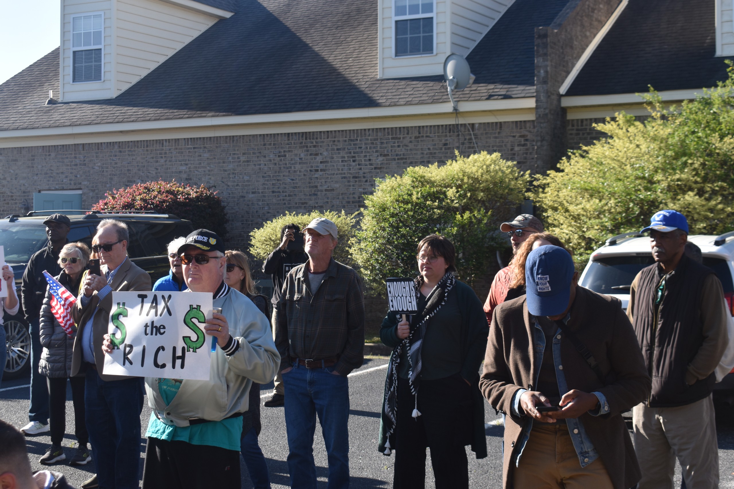 A group of people holding up signs. One sign says, "Eat the Rich."
