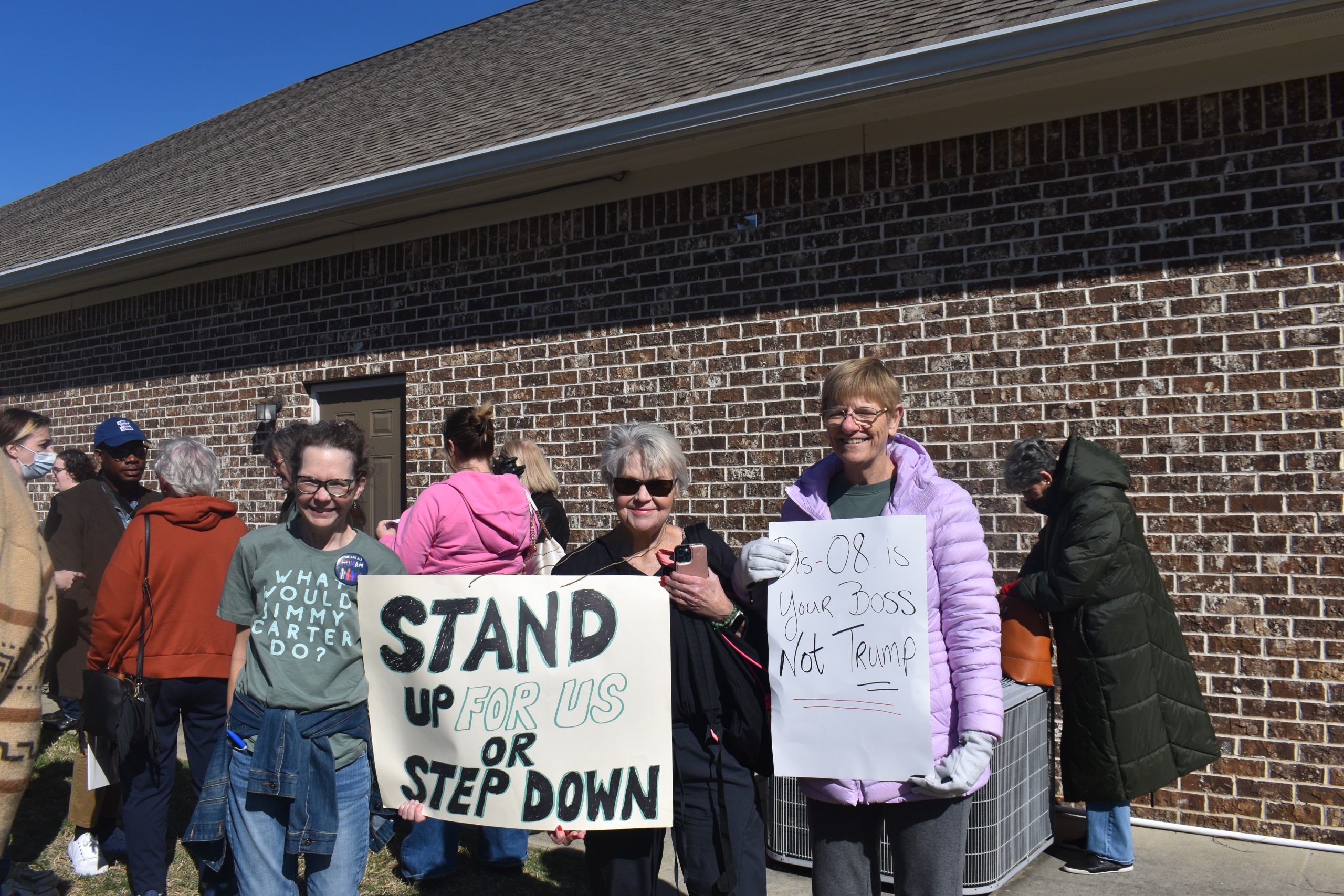 Three women smiling and holding a sign.