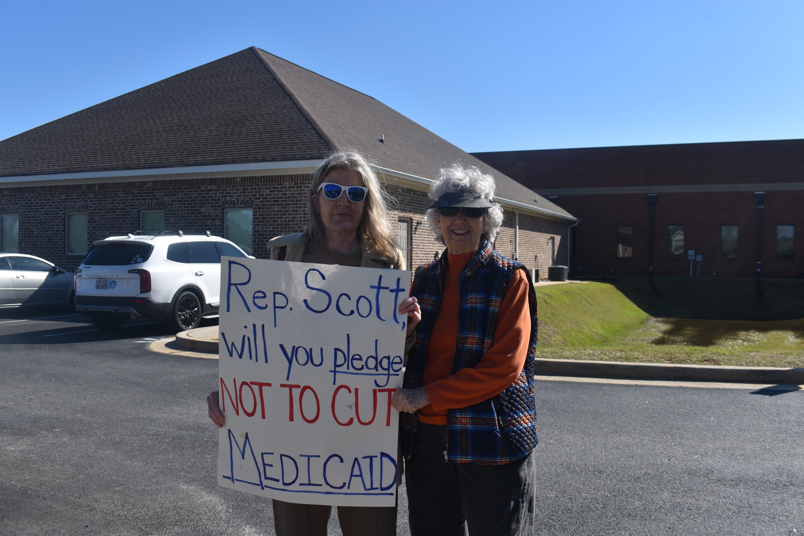 Two women smiling and holding a sign.