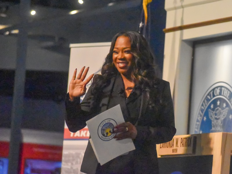 A women smiling and waving at the audience.