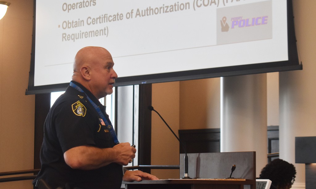A man in a police uniform speaking at a podium.