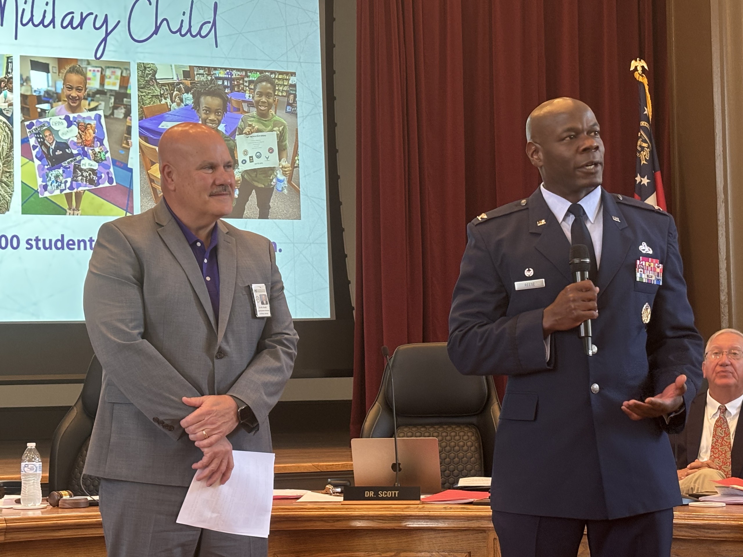 two men, one in a gray suit on the left and the other wearing Air Force uniform on the right