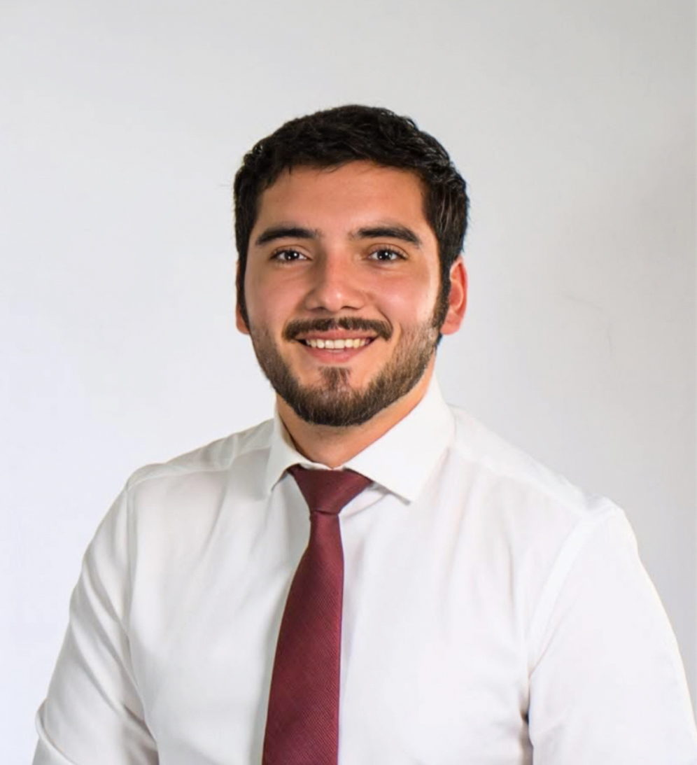 A man in a white button up shirt and red tie smiling.