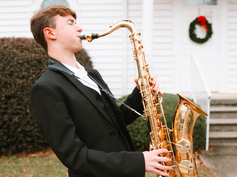 A young man in a tuxedo playing the saxophone.