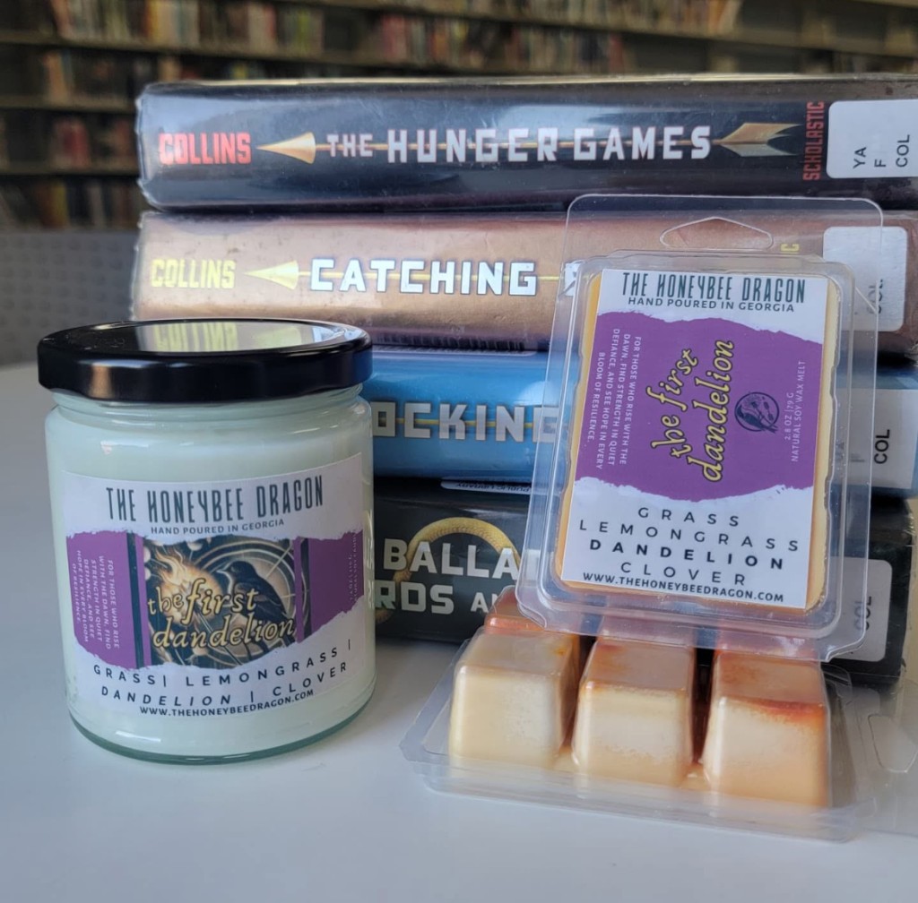 A candle and yellow and orange wax melt against a stack of books.