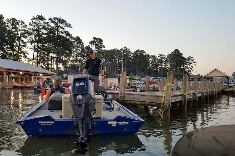 A man standing on a blue boat. The boat is on the water.