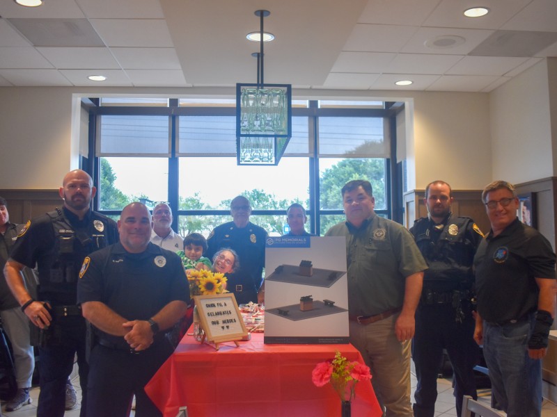 Police officers looking at the camera. There is a red table in the middle and signs on the table.