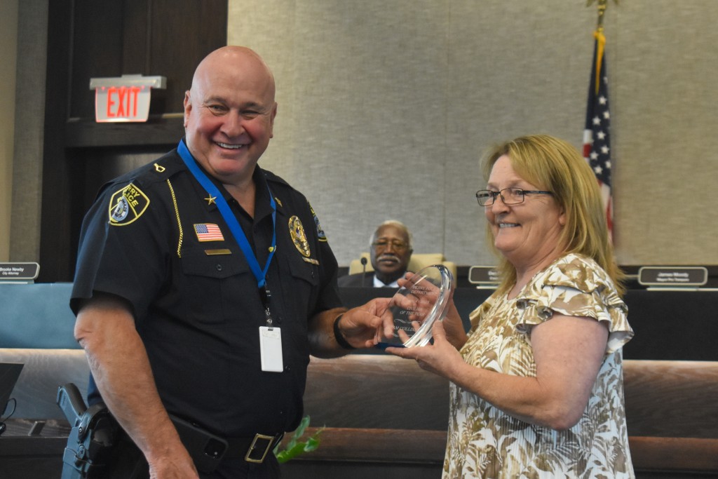 A man in a police uniform smiling with a women. The two are holding a clear object.