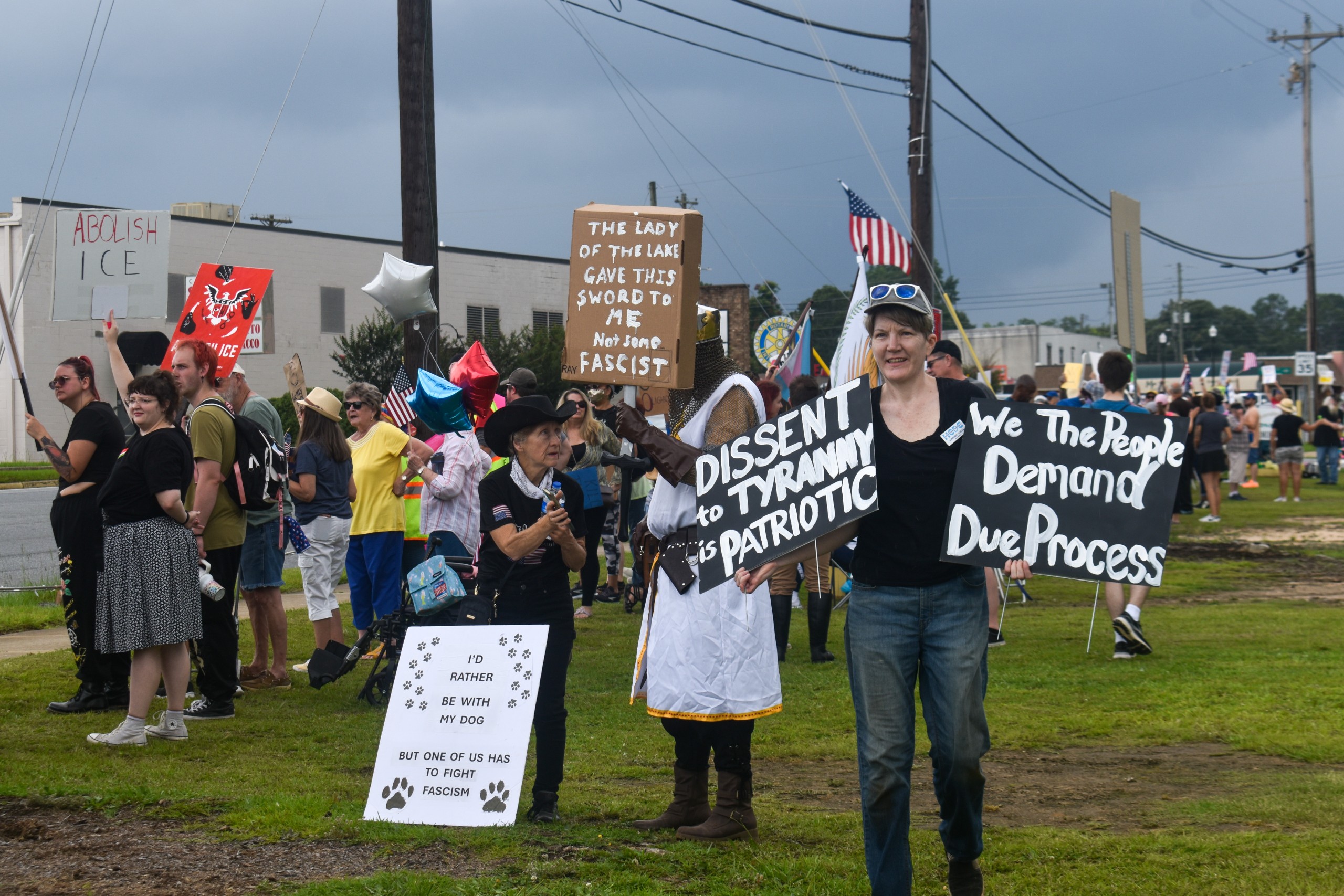 A woman holding two signs condemning Tyranny and demanding due process. The woman is wearing a black shirt. Both signs have a black background and white letters.
