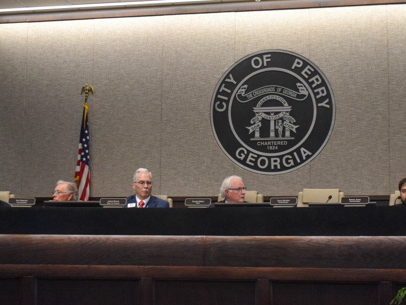 For men sitting in chairs behind a table.