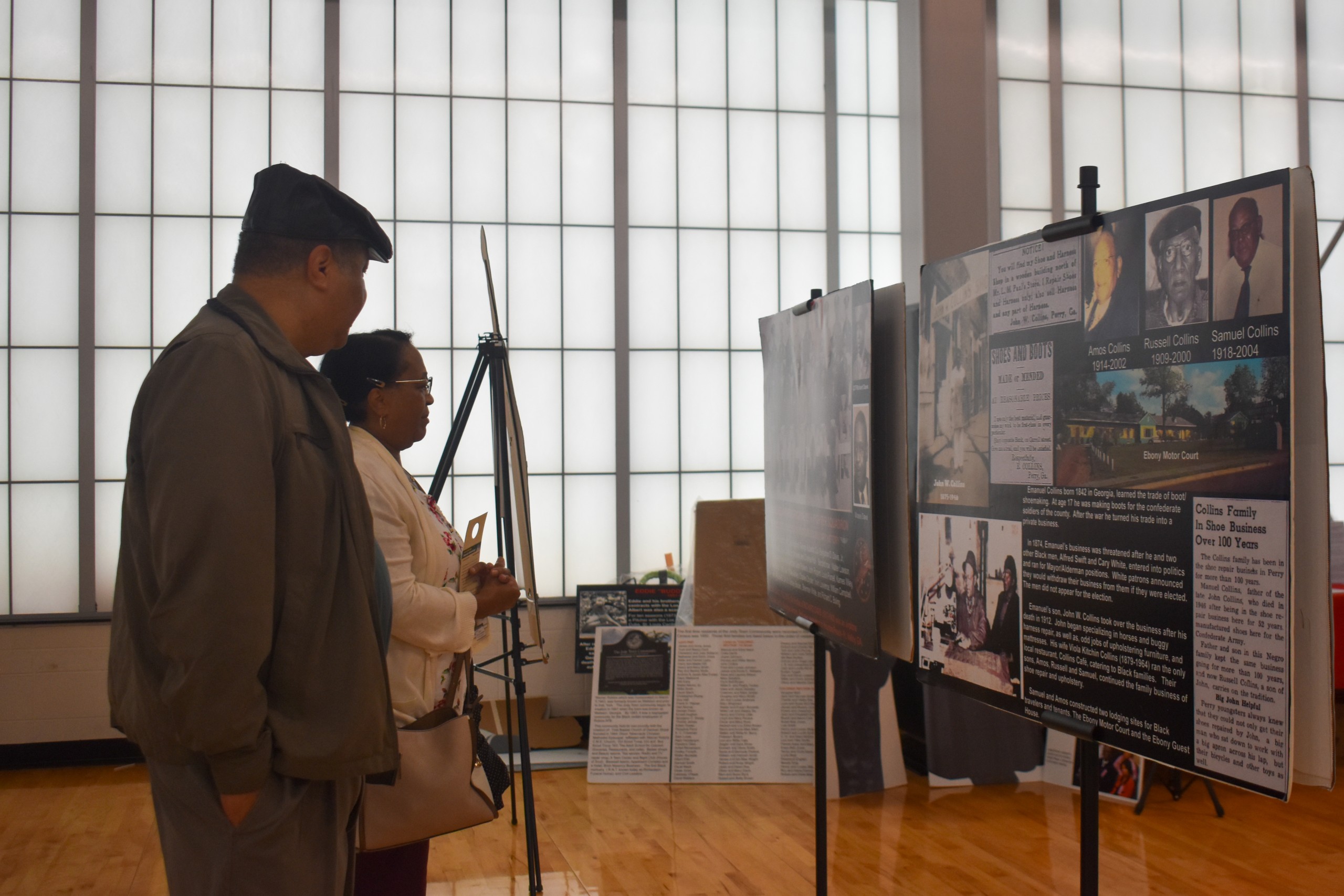 A man wearing a hat and a woman looking at a display.