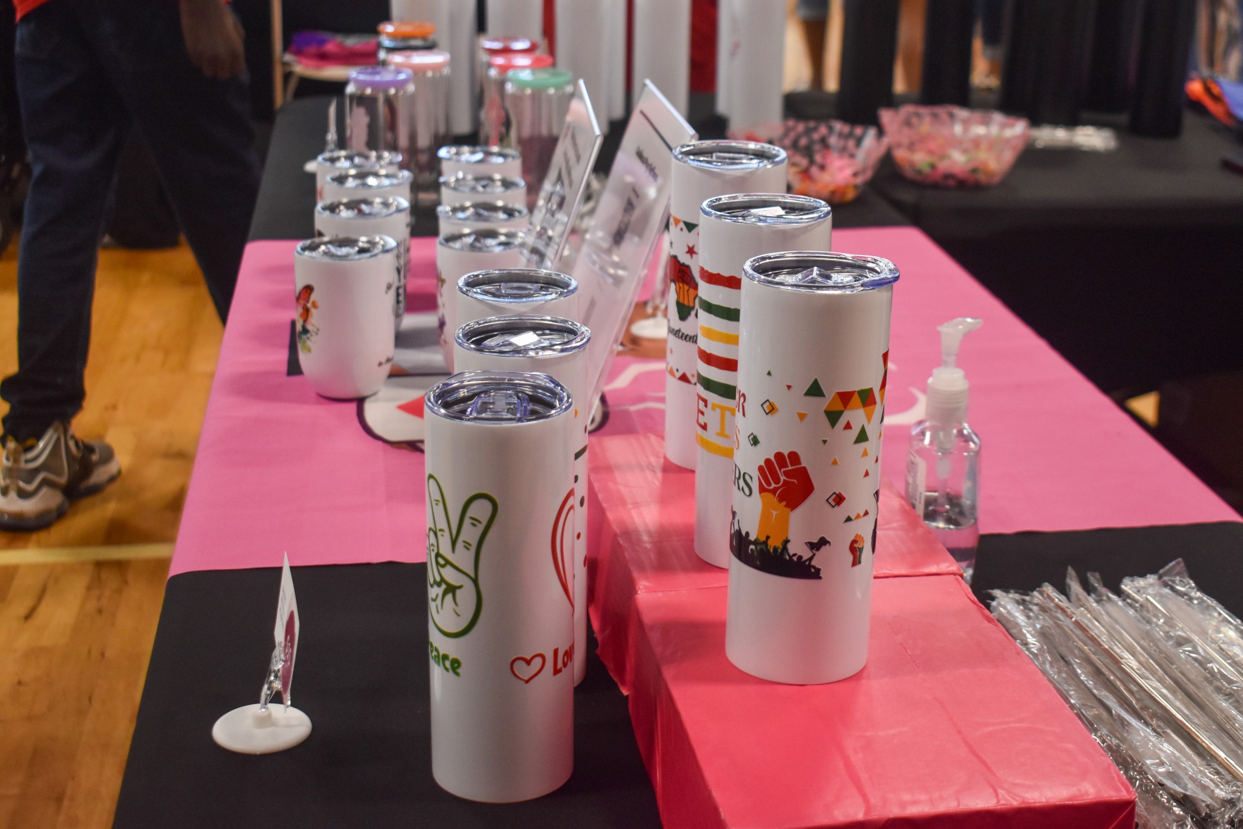 White cups with stickers on them. The stickers have different designs including a red and yellow fist. One of the stickers also has a hand doing a peace sign. The hand is green.