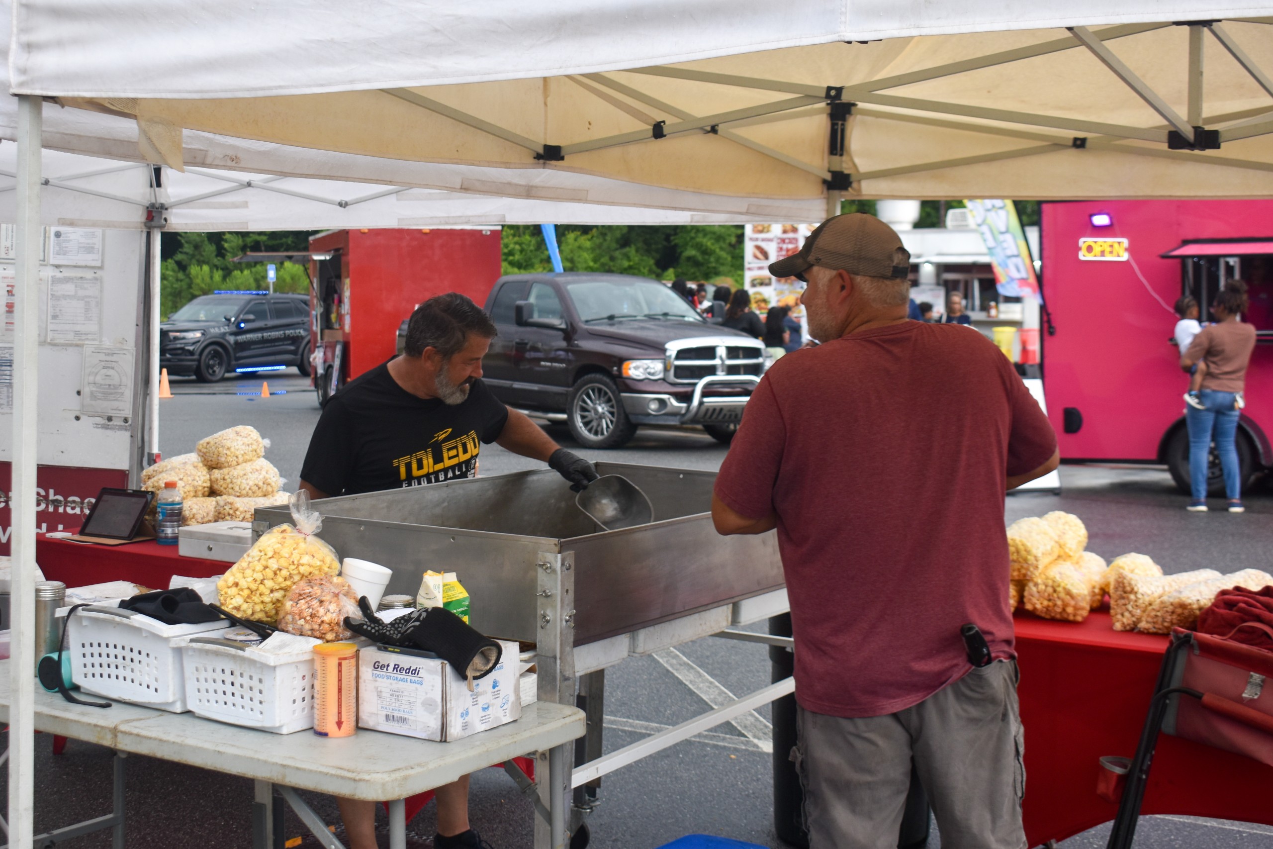 Two men making and selling popcorn outside.