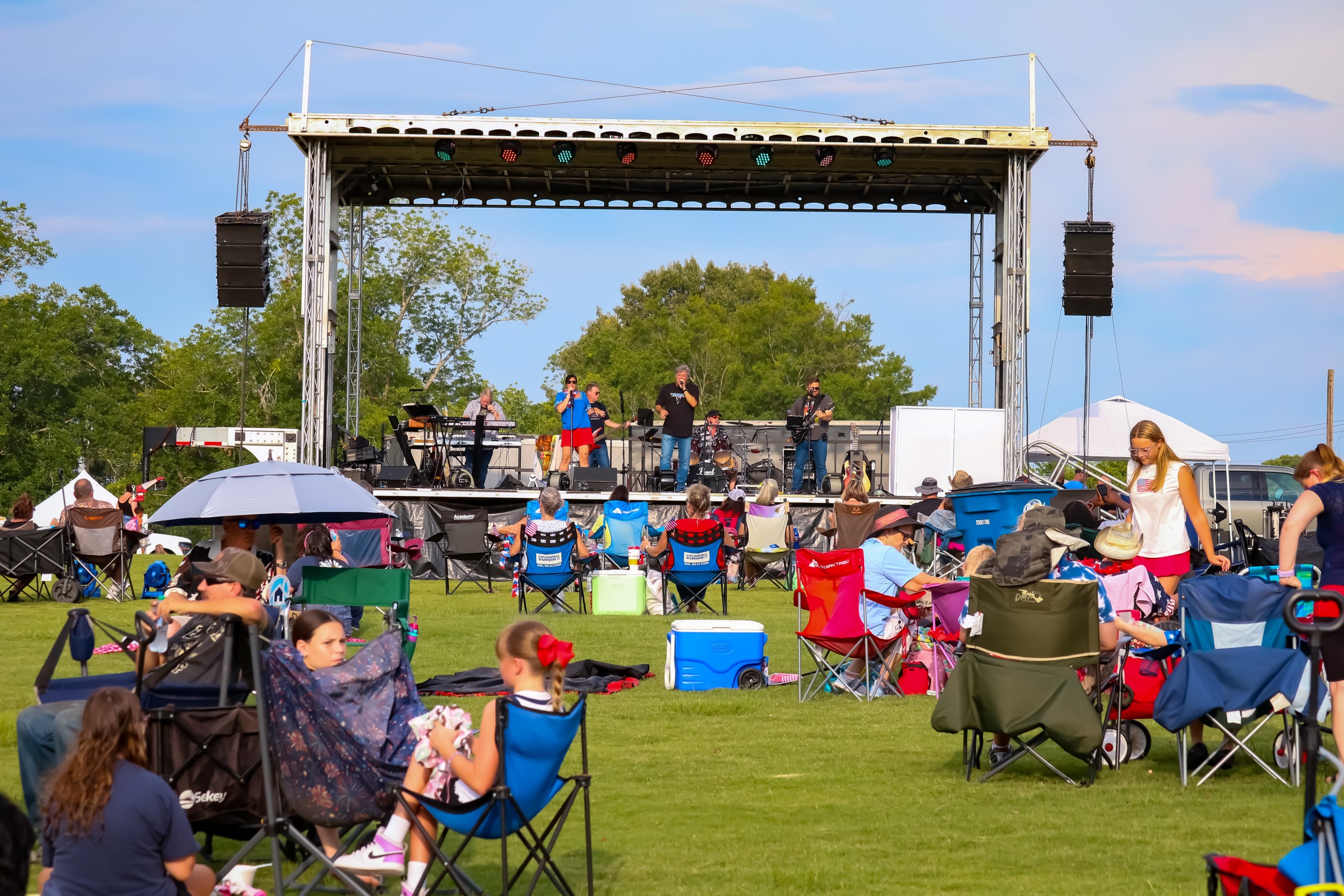 People sitting in lawn chairs in front of a stage.